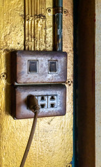 Fototapeta na wymiar Old and dirty electric switches and plugs against gold background.