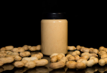 Ripe peanuts in husk and jar with peanutbutter