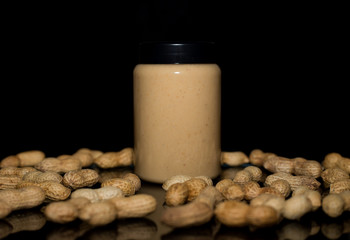 Ripe peanuts in husk and jar with peanutbutter