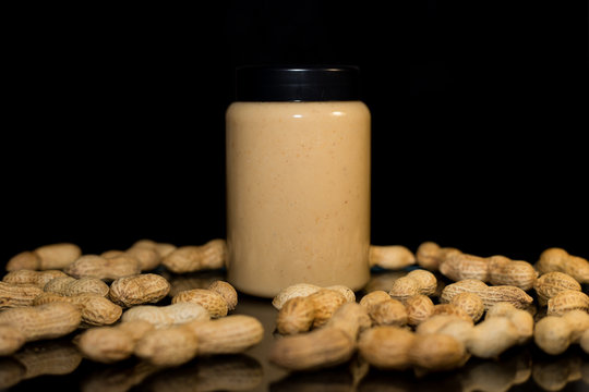 Ripe peanuts in husk and jar with peanutbutter