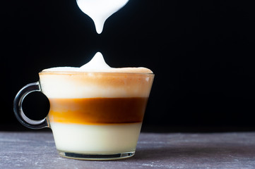 Creating a Cuban Coffee, spooning foamed milk on top.
