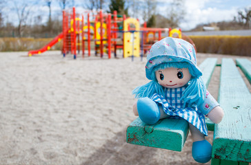 Fototapeta na wymiar forgotten toy doll in the empty quarantined playground