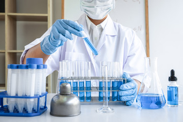 Fototapeta premium Female scientific researcher or doctor working in laboratory about virus and vaccine antiretroviral coronavirus covid19 researcher investigations with test tubes flask and blue liquid solution