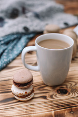 Two homemade colorful macaroons are lying on the brown wooden table with cup of coffee. Cup of...