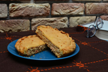 Homemade pie with salmon and cheese. Conceptual image with warm home atmosphere, blanket, glasses and book. Stay home and eat home concept.