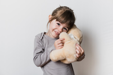 Uen petite fille tenant son ours en peluche avec un masque pendant la période du confinement du...