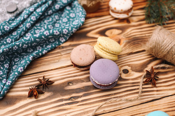 Fototapeta na wymiar Homemade colorful macaroons are lying on the brown wooden table. Cup of coffee. Anise, honey and colorful tissue.