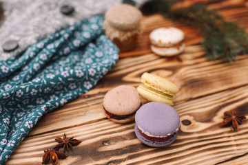 Fototapeta na wymiar Homemade colorful macaroons are lying on the brown wooden table. Cup of coffee. Anise, honey and colorful tissue.