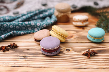 Homemade colorful macaroons are lying on the brown wooden table. Cup of coffee. Anise, honey and colorful tissue.