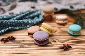 Homemade colorful macaroons are lying on the brown wooden table. Cup of coffee. Anise, honey and colorful tissue.