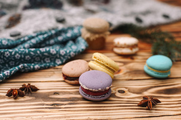 Homemade colorful macaroons are lying on the brown wooden table. Cup of coffee. Anise, honey and colorful tissue.