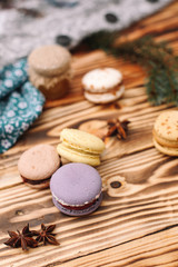 Homemade colorful macaroons are lying on the brown wooden table. Cup of coffee. Anise, honey and colorful tissue.
