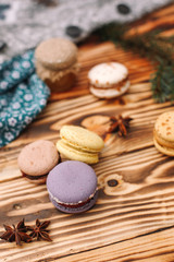 Homemade colorful macaroons are lying on the brown wooden table. Cup of coffee. Anise, honey and...