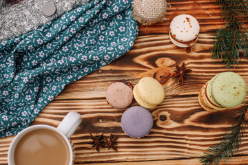 Fototapeta na wymiar Homemade colorful macaroons are lying on the brown wooden table with cup of coffee. Cup of coffee. Anise, honey and colorful tissue.