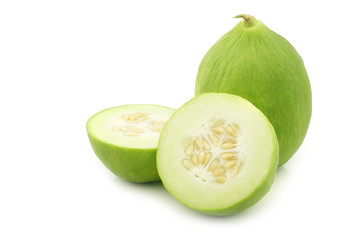 Two cumelo's (mix between a cucumber and a melon) and a cut one on a white background