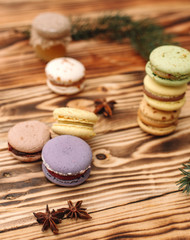 Fototapeta na wymiar Homemade colorful macaroons are lying on the brown wooden table. Cup of coffee. Anise and honey.