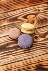 Three homemade colorful macaroons are lying on the brown wooden table with cup of coffee with the place for text. Colors.