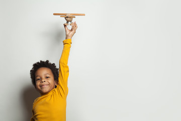Little black child boy with plane model on white background