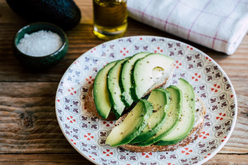 Tartines de pain de campagne avec des lamelles d'avocat assaisonnée à l'huile d'olive et poivre