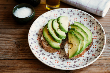 Tartines de pain de campagne avec des lamelles d'avocat assaisonnée à l'huile d'olive et poivre