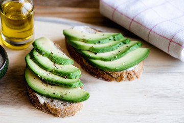 Tartines de pain de campagne avec des lamelles d'avocat assaisonnée à l'huile d'olive et poivre