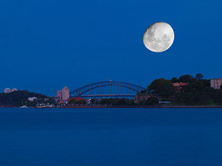 Obraz premium Sydney harbour illuminated by the moon and circular quay with vibrant colourful lights at midnight in NSW Australia