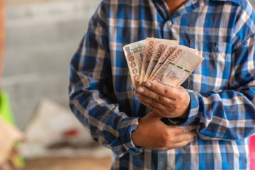 The hands of the construction workers holding banknotes and mobile phones