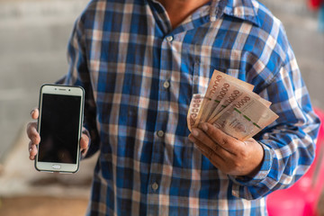 The hands of the construction workers holding banknotes and mobile phones