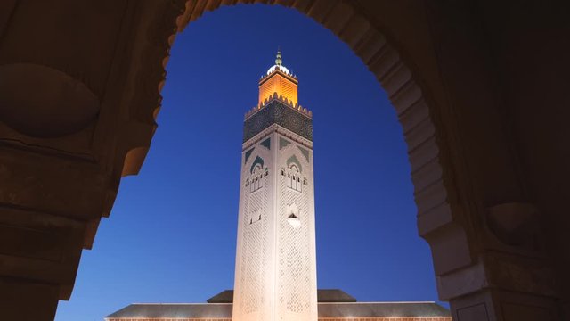 dusk view of the minaret of hassan ii mosque framed by an arch in casablanca, morroco