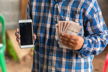 The hands of the construction workers holding banknotes and mobile phones