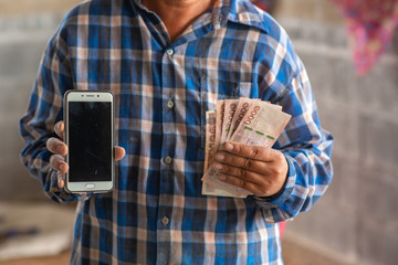 The hands of the construction workers holding banknotes and mobile phones