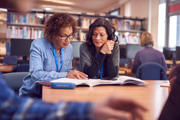 Teacher With Mature Female Adult Student Sitting At Table Working In College Library - Powered by Adobe