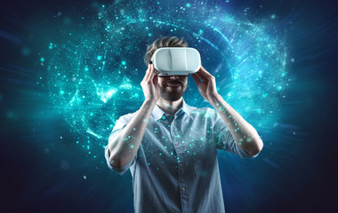 Junger Mann schaut durch VR-Brille und taucht in virtuelle Welt ein