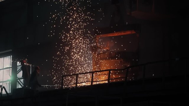 Bright Splash of Sparks in the Steel Making Plant Factory Workers in the Foundry Dark Background Heavy and Dangerous Work Metallurgy Slow Motion