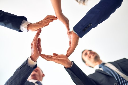 Group of business workers smiling happy and confident. Standing on a circle with smile on face doing symbol with hands together at the office.