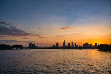 Naklejka premium River city view landscape at twilight sunset. Boat on river with tranquil water. Hochiminh city Saigon vietnam cityscape building with Bitexco tower