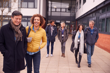 Group Of Smiling Mature Students Walking Outside College Building