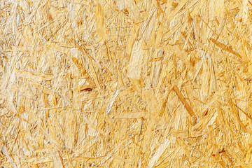 Fragment of molded slabs made from wood waste and recycled Euro pallets. Patterns and textures of veneer. Particle Board yellowish beige color, wood background. The concept of recycling wood