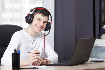 Teenager with headphones is sitting at a laptop the concept of online learning