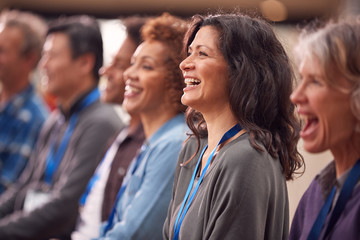 Group Of Casually Dressed Businessmen And Businesswomen Listening To Presentation At Conference