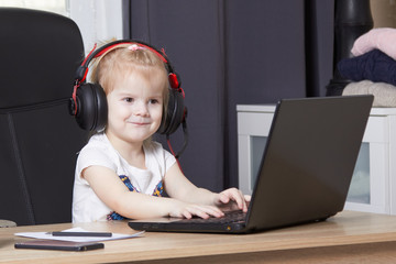 little girl in a big chair and headphones online education concept