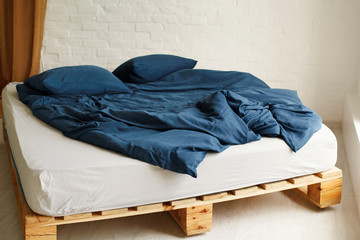 Picture of wooden bed with blue bed linen in bright bedroom
