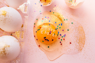 From above broken Happy Easter egg decorated with sparkles and colorful stars on pink background