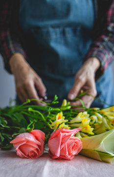 Unrecognizable female professional florist making bouquets of various types. Roses. Yellow flowers. Coves