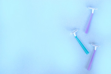 disposable razors of different colors on a blue background