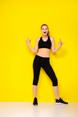 young woman doing exercise on yellow background