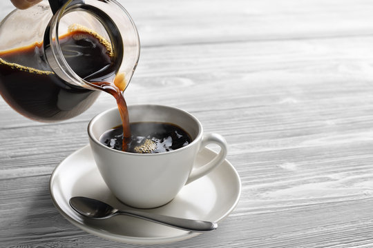 Pouring coffee with smoke on a cup on wooden background