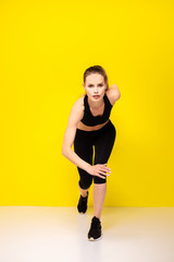 young woman doing exercise on yellow background