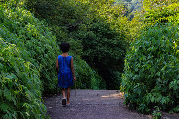 A small girl walking in a park with green background