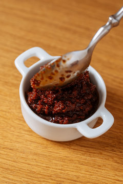 From above spoon in small bowl with tasty sauce on wooden table in kitchen